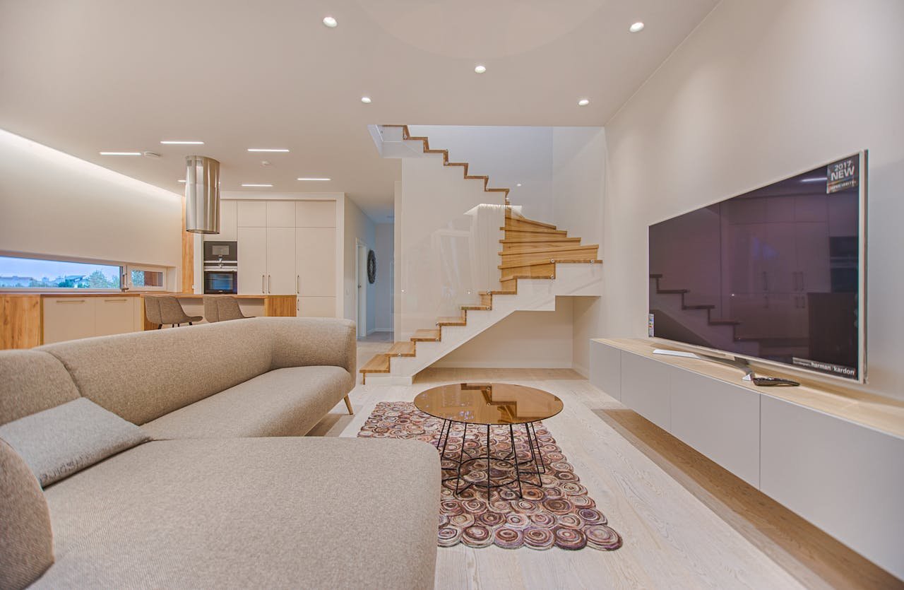 services-img-02 Spacious modern living room featuring stairs, a TV, and sleek furniture design.